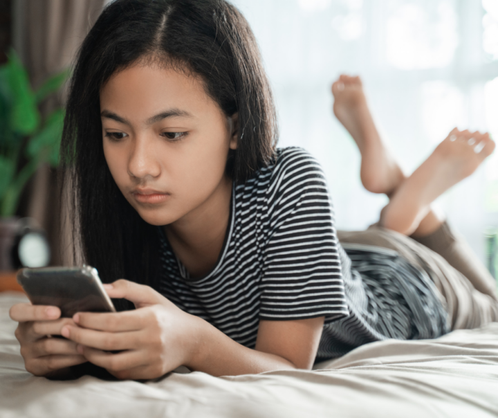 Young girl on bed looking at her phone